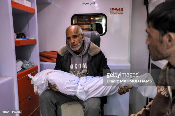Graphic content / The grandfather of Sidal Abu Jamea, a Palestinian girl from Khan Yunis, carries her wrapped body after she died overnight while...