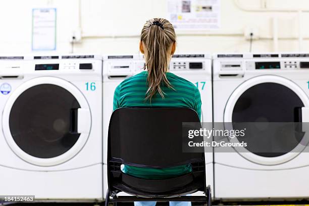 woman watching a laundry machine washing her load of clothes - bored housewife stock pictures, royalty-free photos & images