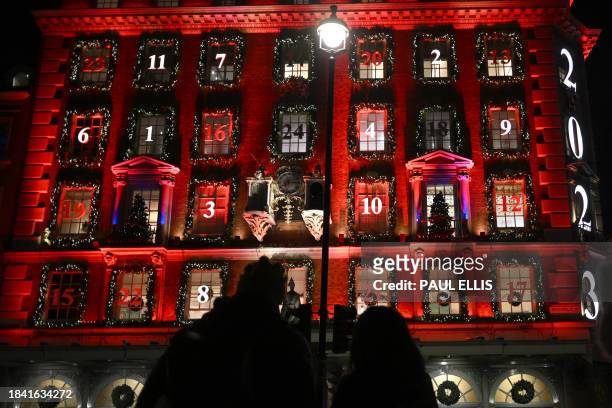 Pedestrians look at the facade of the Fortnum and Mason store, illuminated for Christmas, on Piccadilly in London on December 11, 2023. The store...