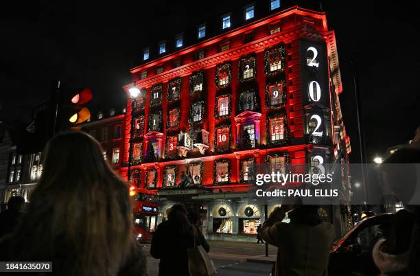 Pedestrians look at the facade of the Fortnum and Mason store, illuminated for Christmas, on Piccadilly in London on December 11, 2023. The store...