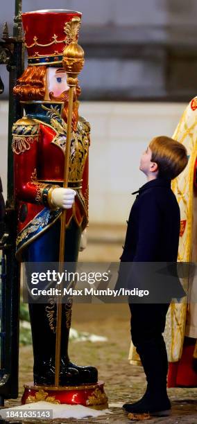 Prince Louis of Wales looks at an oversized decorative Nutcracker soldier as he attends The 'Together At Christmas' Carol Service at Westminster...