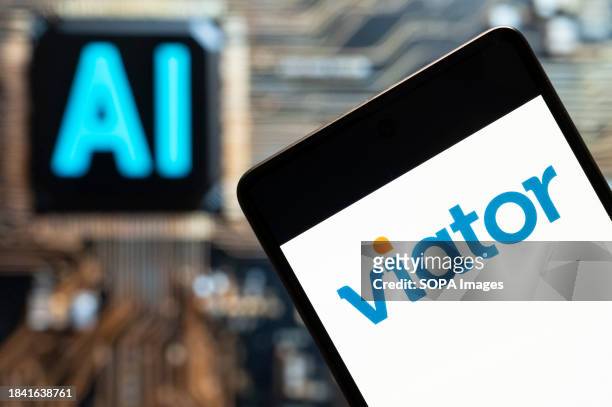 In this photo illustration, the online travel search engine website Viator logo seen displayed on a smartphone with an Artificial intelligence chip...
