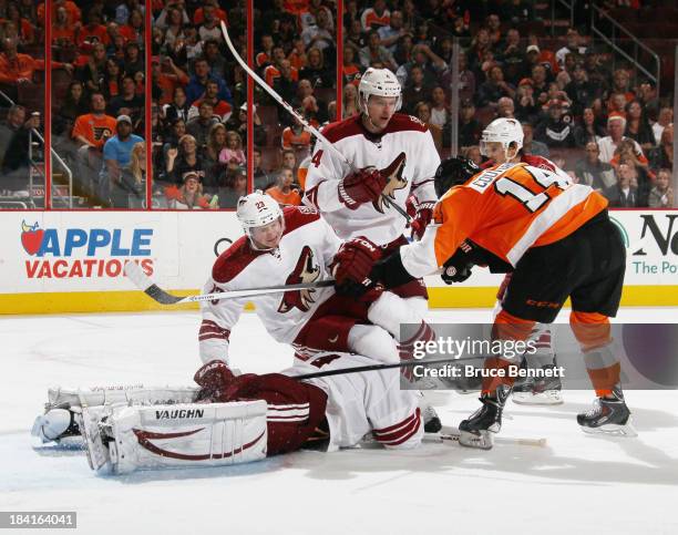 Sean Couturier of the Philadelphia Flyers pushes Oliver Ekman-Larsson of the Phoenix Coyotes over hit goaltender Thomas Greiss during the second...