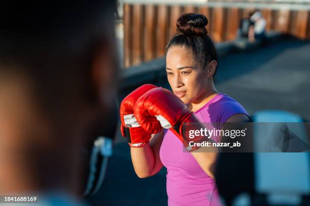 frau mit boxhandschuhen beim schlagen im freien. - frauen kickboxen stock-fotos und bilder