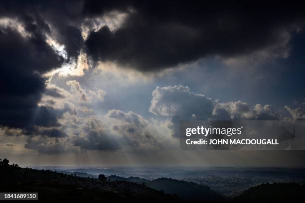 The sun pierces through dark clouds near the town of Kharas, north of Hebron in the occupied West Bank on December 6, 2023. With most of the town's...