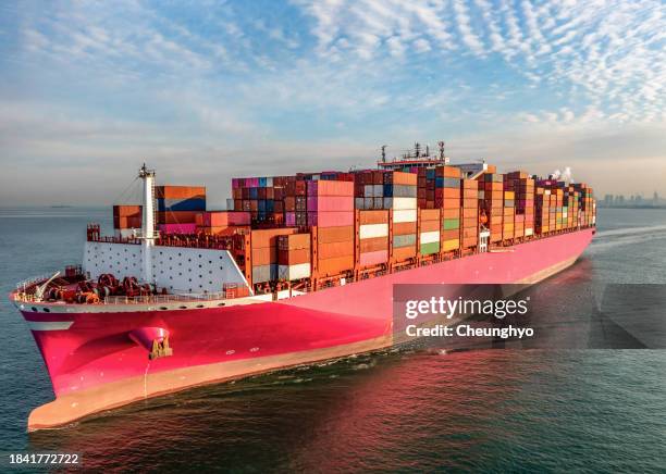 a pink color freighter full of containers is sailing into loading dock of qingdao new qianwan container terminal. east china's shandong province - contenedor de carga fotografías e imágenes de stock