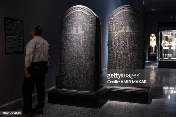 Visitor reads the caption near the identical stelae of the decree of Nectanebo I , recovered from the sunken ruins of the ancient city of Naukratis...