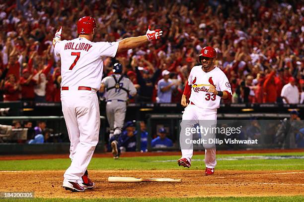 Daniel Descalso scores the game winning run as Matt Holliday of the St. Louis Cardinals greets him at home plate in the 13th inning against the Los...