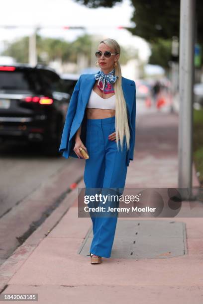 Denisa Palsha seen wearing white sunglasses, Louis Vuitton gold logo earrings, Louis Vuitton blue / pink / white colorful pattern silk scarf, white...