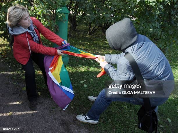Gay rights activist fights for her rainbow flag against an anti-gay protester during a gay pride event in Saint Petersburg on October 12, 2013....