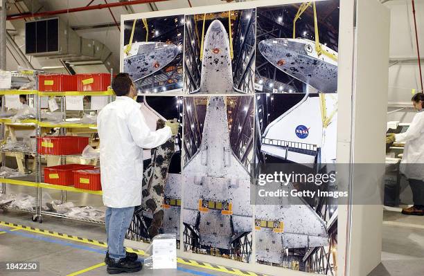 In this NASA handout photo, a NASA crash investigator compares debris from the Space Shuttle Columbia to a photograph of the Shuttle in a hangar...