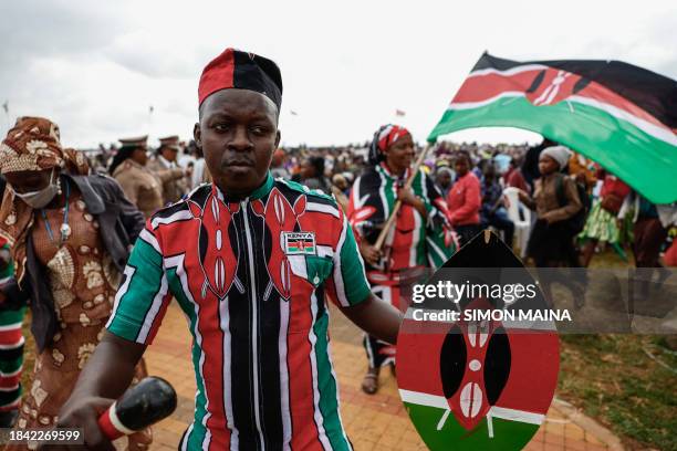 Member of public holds a shield with the Kenyan national flag colours attends the national celebration marking Kenya's 60th anniversary of...