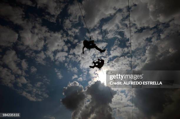 People hang from cables during the first Day of the Corona Capital Music Fest at the Hermanos Rodriguez racetrack, in Mexico City, on October 12,...