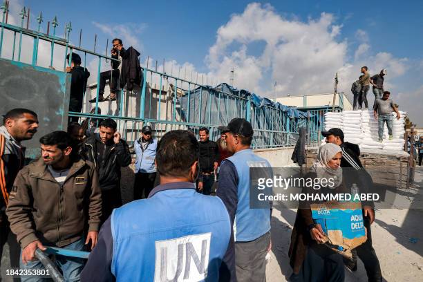 Workers of the United Nations Relief and Works Agency for Palestine Refugees hand out flour rations and other supplies to people at an UNRWA...