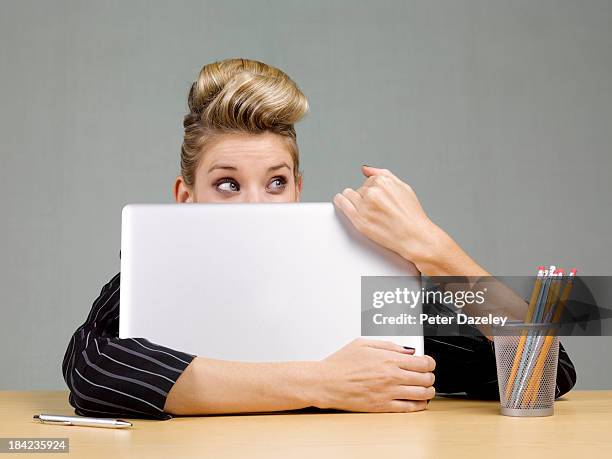 guilty businesswoman behind laptop - embarrassment stock-fotos und bilder