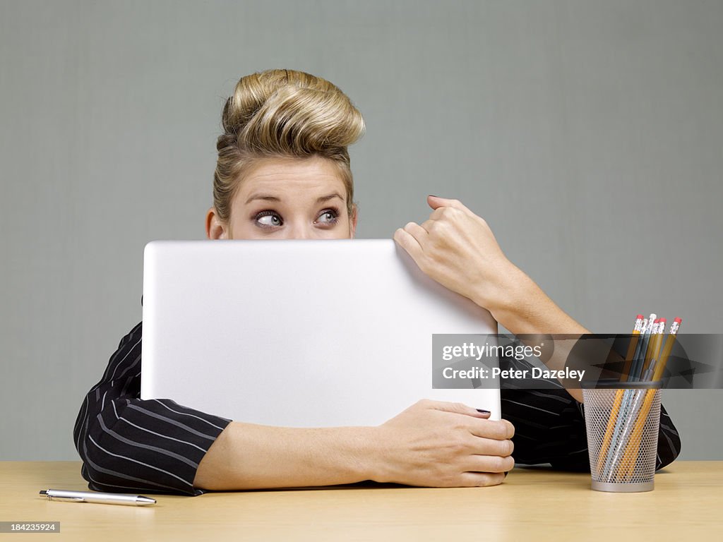 Guilty businesswoman behind laptop