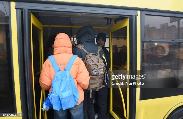 Passengers are getting on a bus that is operating between the closed metro stations of the Blue Line in Kyiv, Ukraine, on December 11, 2023. Train...