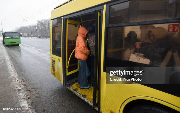 Passengers are getting on a bus that is operating between the closed metro stations of the Blue Line in Kyiv, Ukraine, on December 11, 2023. Train...