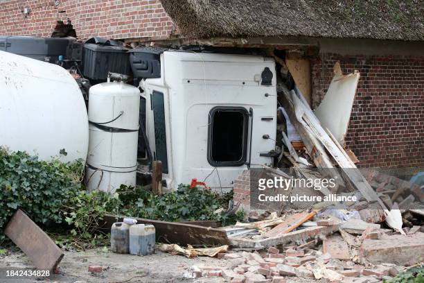 December 2023, Schleswig-Holstein, Blomesche Wildnis: A concrete mixer lies on its side after crashing into a house. A multi-axle concrete mixer with...