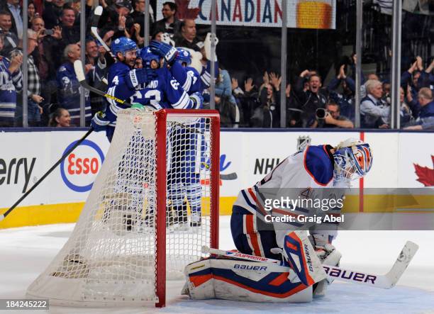 Dave Bolland of the Toronto Maple Leafs celebrates his overtime goal with teammates as Devan Dubnyk of the Edmonton Oilers looks on during NHL game...