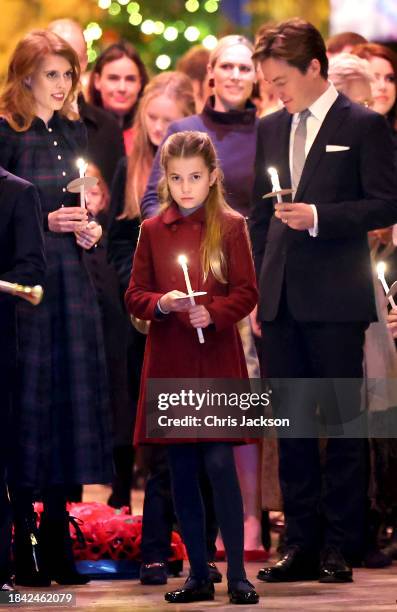 Princess Charlotte of Wales holds a candle as she leaves with her family at The "Together At Christmas" Carol Service at Westminster Abbey on...