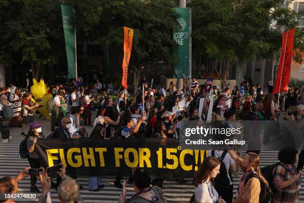 Activists, including some holding a banner that reads: "Fight for 1.5 degrees Celsius!!!", march in protest on day nine of the UNFCCC COP28 Climate...