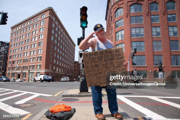 Vietnam War veteran salutes passerbys as he panhandles for money on streets of Boston, MA.