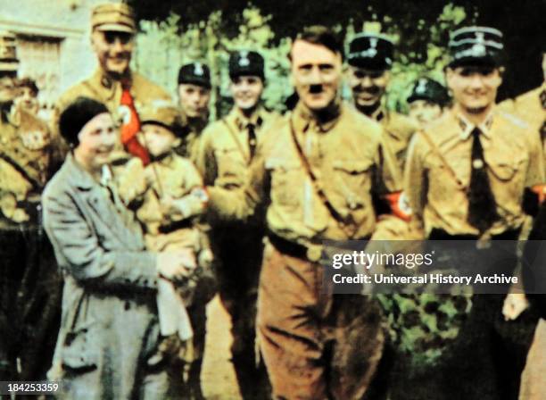 Hitler greets a German Nazi mother with child dressed in Nazi uniform circa 1932-33