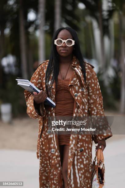 Iyanna Yasmeen seen wearing Gucci white round glasses, brown ruffled short dress, Burberry brown pattern long coat, Louis Vuitton white canvas with...