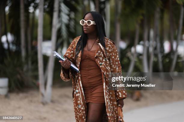 Iyanna Yasmeen seen wearing Gucci white round glasses, brown ruffled short dress, Burberry brown pattern long coat, Louis Vuitton white canvas with...