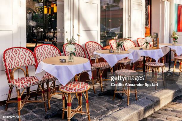 tables at the sidewalk cafe in montmartre on a sunny day, paris, france - paris cafe stock pictures, royalty-free photos & images