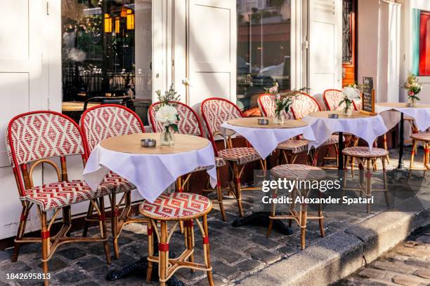tables at the sidewalk cafe in montmartre on a sunny day, paris, france - café esplanada imagens e fotografias de stock