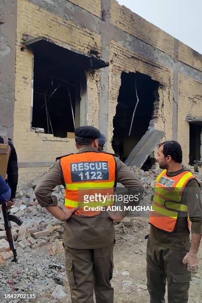 Rescuers stand at the site of attack after militants rammed an explosive-laden vehicle into a Pakistan military base, in the town of Daraban of Dera...