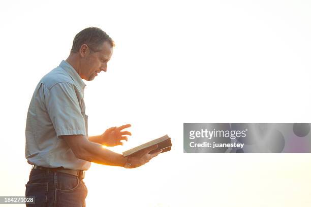 pastor casually dressed walking in sunlight reading bible - preacher stock pictures, royalty-free photos & images