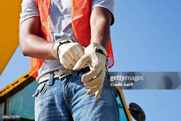 travailleur de la construction sur site, mettre des gants - protective workwear photos et images de collection