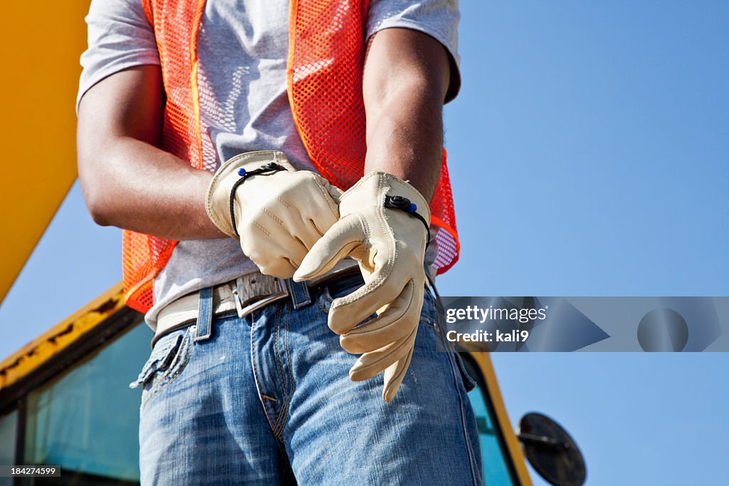 Operaio in cantiere mettendo su guanti