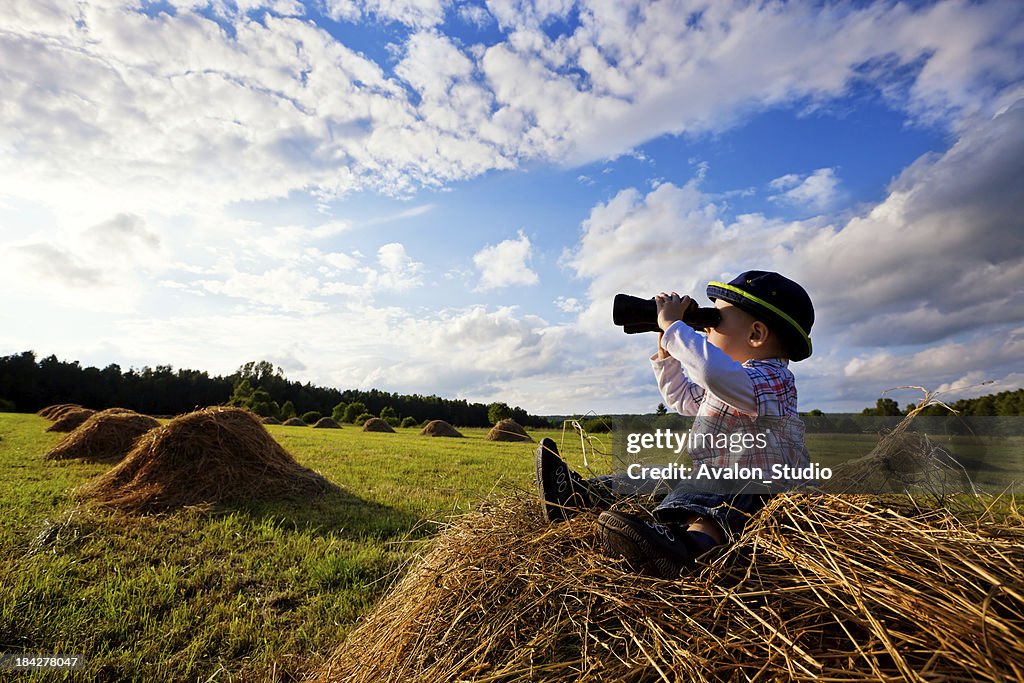 Little boy sitting on mounds of hay