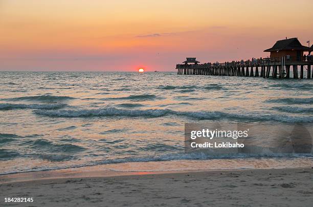 sun sinks below horizon at gulf of mexico - naples pier stock pictures, royalty-free photos & images