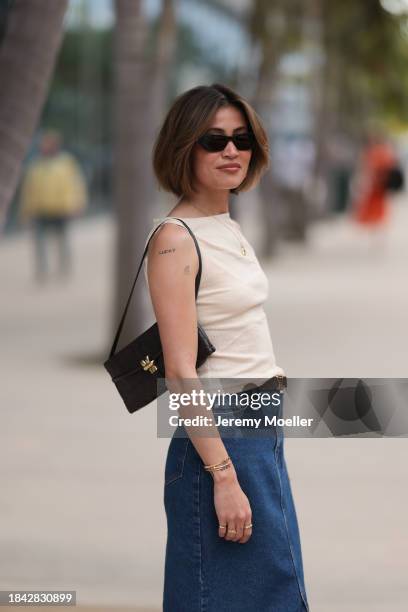 Michelle Fleur seen wearing Saint Laurent black sunglasses, cream white sleeveless top, gold letter necklace, Louis Vuitton brown canvas logo pattern...