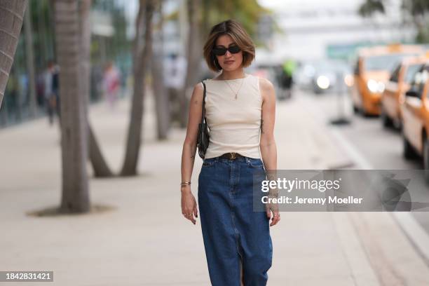 Michelle Fleur seen wearing Saint Laurent black sunglasses, cream white sleeveless top, gold letter necklace, Louis Vuitton brown canvas logo pattern...