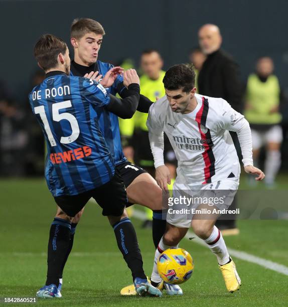 Christian Pulisic of AC Milan is challenged by Marten de Roon and Charles De Ketelaere of Atalanta BC during the Serie A TIM match between Atalanta...