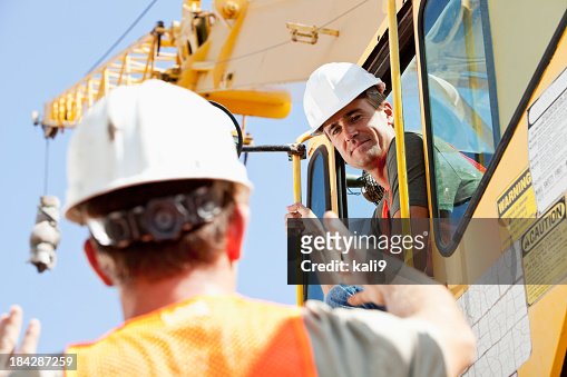 Construction worker talking to crane operator
