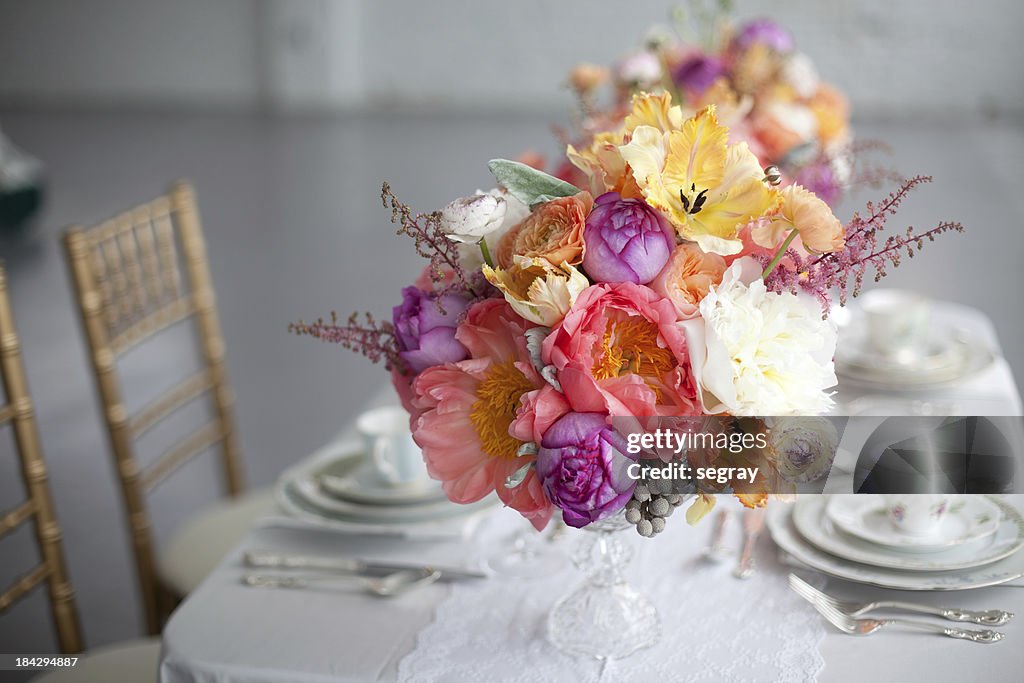 Gedeckter Tisch mit Blumenmuster und Gestecke