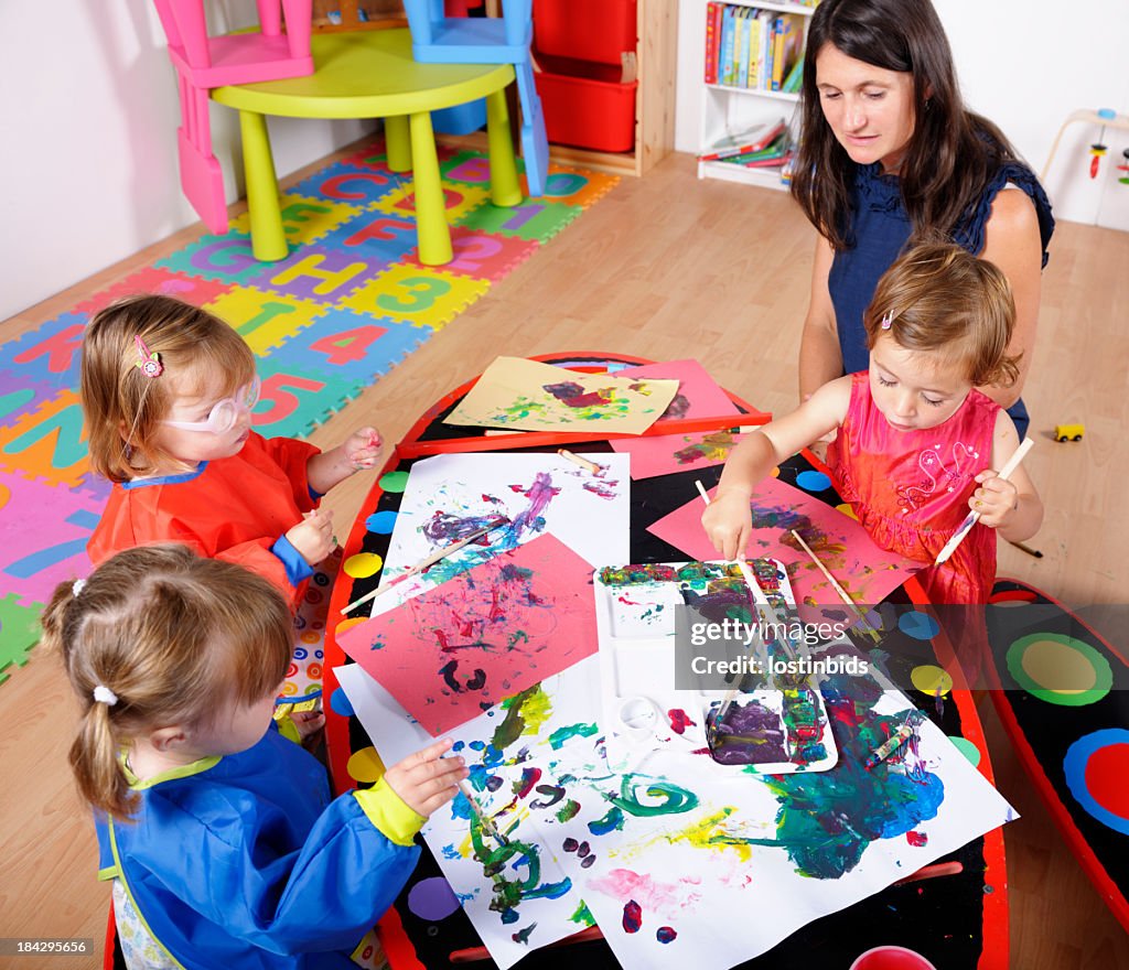 Toddlers Doing Art And Craft Under Carer's/ Childminder's Supervision