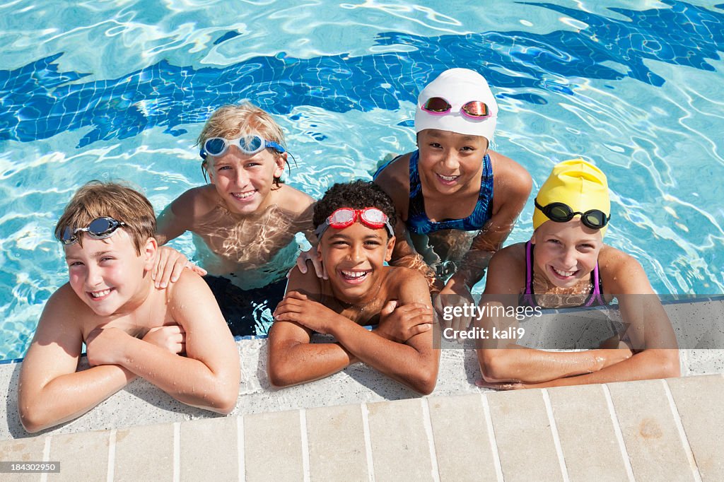 Groupe multi-ethnique de cinq enfants dans la piscine