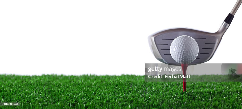 Golf club next to golf ball on red tee on grass