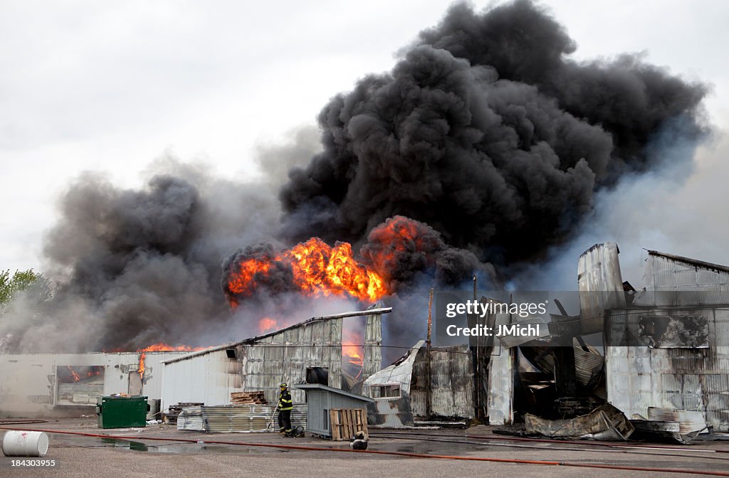 An old warehouse on fire with black smoke