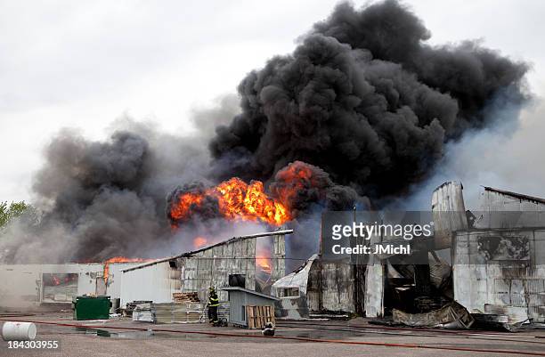 an old warehouse on fire with black smoke  - rubble stock pictures, royalty-free photos & images