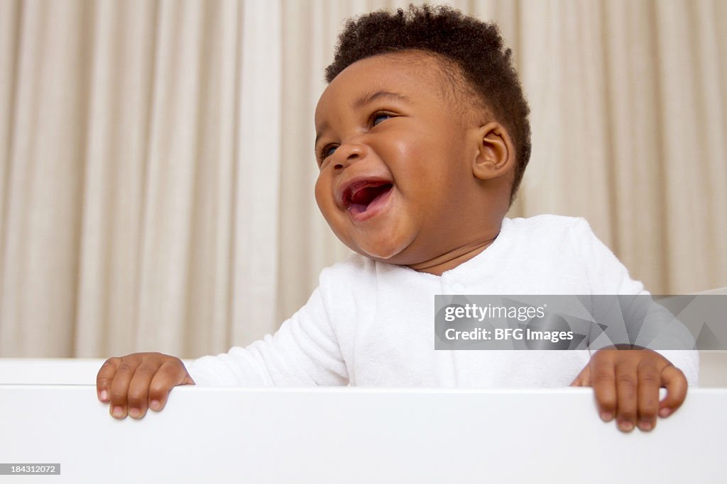 Happy African baby boy standing in crib, Cape Town, South Africa