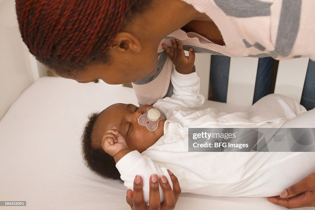 Close Up Of African Mother Putting Baby Down In Crib Cape Town South close-up-of-african-mother-putting-baby-down-in-crib-cape-town-south